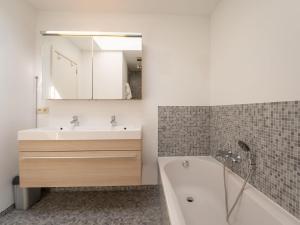 a bathroom with a tub and a sink and a mirror at Apartment Albatros with parking by Interhome in Bredene