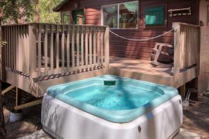 un bain à remous sur une terrasse avec une maison dans l'établissement Beetlebark Bungalow- Inside Yosemite w/ hot tub EV charging cable, à North Wawona