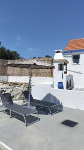 two lounge chairs and an umbrella on a patio at Sea Breeze Stegna in Archangelos +43 photos