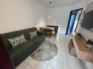 a living room with a green couch and a table at Casa em Curitiba perto da Pedreira e Opera de Arame, com Ar Condicionado 3Quartos in Curitiba