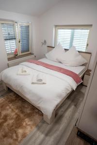 a large white bed in a bedroom with two windows at OPG Lukaček in Glogovac