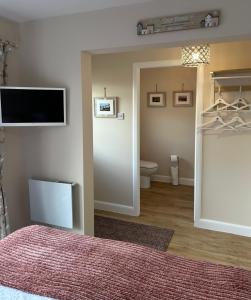 a bedroom with a bed and a tv and a toilet at Stepping Stone in Fort William