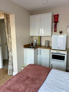 a small kitchen with white cabinets and a bed at Stepping Stone in Fort William