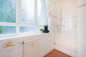 a white bathroom with a shower and a sink at Schöne Ferienwohnung in Xanten in Xanten +20 photos