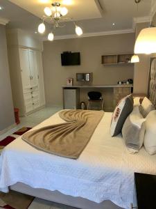 a bedroom with a large bed with white sheets and pillows at On Hill Lodge in Bloemfontein