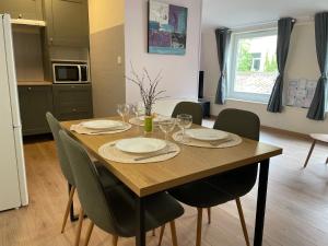 a wooden table with chairs and plates and wine glasses at L'olive - cuisine équipée, centre ville, fibre in Ardres