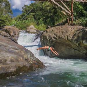 a person laying on a rock in a river at Charming Cosy Chirripó Mountain Riverfront Cottage in Canaán