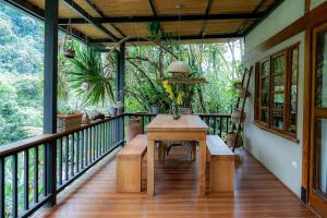 a porch with a table and benches on a balcony at Charming Cosy Chirripó Mountain Riverfront Cottage in Canaán