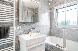 Un baño con lavabo, bañera y espejo. en See Oase, en Uhldingen-Mühlhofen 15 fotos más