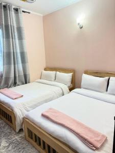 two twin beds in a room with a window at Logic stays 3 bedroom Arusha, Njiro in Arusha