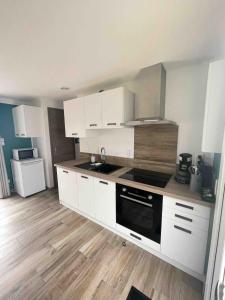 a kitchen with white cabinets and a wooden floor at Le petit Chatel in Hattonchâtel +6 photos