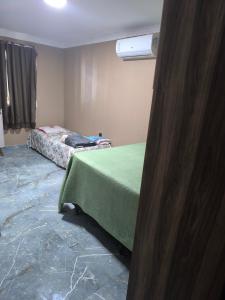 una stanza con un letto con un copriletto verde e una stanza con di Casa de praia a Ilhéus