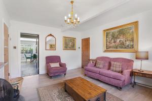 a living room with two purple couches and a table at Spindlestone Cottage - North East Escapes in Bamburgh +21 photos