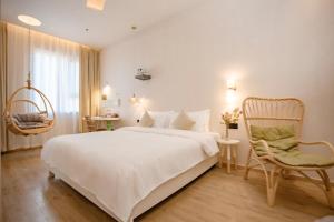a bedroom with a large white bed and a chair at EUPHORIA丨Quiet Garden Quiet Designer Garden Hotel丨Datang Never Sleeps City Big Wild Goose Pagoda Subway Station Branch丨Near the scenic area in Xi'an
