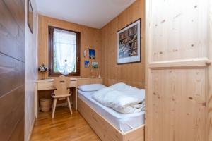 a small bedroom with a bed and a desk at Chalet Baranci in Pozza di Fassa
