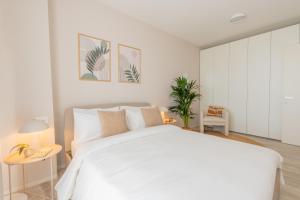 a white bedroom with a large bed and two tables at Vibra Tahiti Prestige in Lido di Jesolo +22 photos
