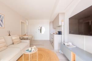 a living room with a white couch and a tv at Vibra Tahiti Prestige in Lido di Jesolo