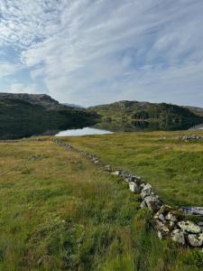 a stone wall in a field next to a body of water at Wild Norwegian nature, between Preikestolen & Trolltunga in Sauda