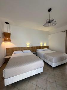 two beds in a hotel room with white sheets at Tsimiklis Apartments in Finikounta