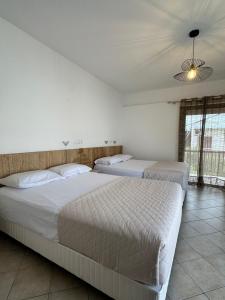 two beds in a bedroom with a ceiling at Tsimiklis Apartments in Finikounta