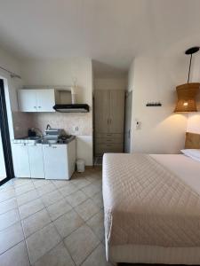 a bedroom with a white bed and a kitchen at Tsimiklis Apartments in Finikounta