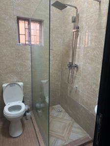 a bathroom with a toilet and a glass shower at Aqua black studio room in Lagos