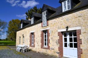 a brick building with a white door and a table at Maison Le Landais in Grandcamp-Maisy