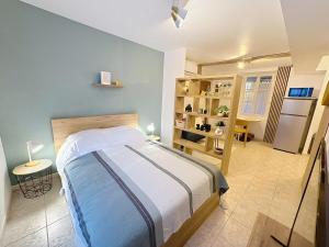 a bedroom with a bed and a kitchen with a refrigerator at Studio Centre Ville Tarbes in Tarbes