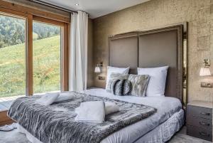 ein Schlafzimmer mit einem großen Bett mit einem großen Fenster in der Unterkunft JAMES TAMG24 - Stunning ski in ski out luxury chalet with indoor pool & cinema in Praz-sur-Arly