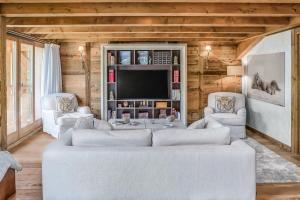 ein Wohnzimmer mit einem weißen Sofa und einem Fernseher in der Unterkunft JAMES TAMG24 - Stunning ski in ski out luxury chalet with indoor pool & cinema in Praz-sur-Arly