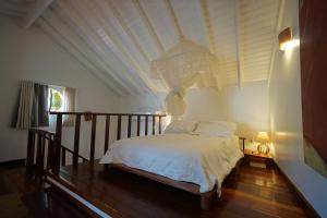a bedroom with a white bed with a wooden floor at Casa da Ilha & SPA in Abraão