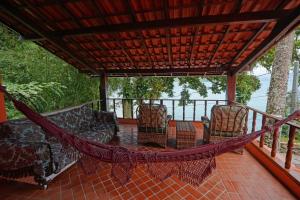 a hammock on a screened in porch with chairs at Casa da Ilha & SPA in Abraão