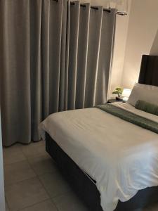 a bedroom with a bed with gray curtains at Cozy nest apartment in Pretoria