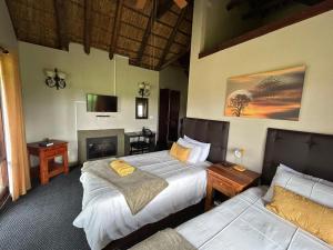 a bedroom with two beds and a fireplace at Koro Lodge in Modimolle +21 photos