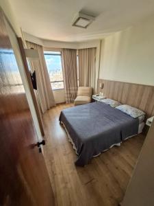 a bedroom with a bed and a chair and a window at Lindo Apto Flat Aconchegante e Mobiliado em Campinas !!! in Campinas
