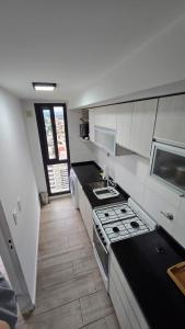 une cuisine blanche avec une cuisinière et un évier dans l'établissement Betania Plaza Premium, Piso17 - BY INMOVE TEMPORARIOS, à Córdoba
