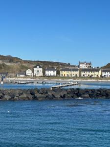 a large body of water with buildings in the background at Church Bay House Rathlin in Rathlin Island +14 photos