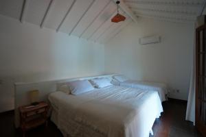 a white bedroom with a bed and a night stand at Casa da Ilha & SPA in Abraão