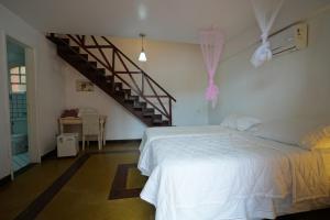 a bedroom with a white bed and a staircase at Casa da Ilha & SPA in Abraão
