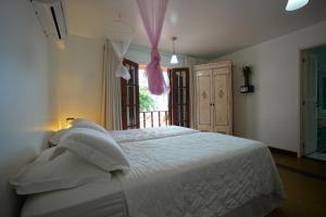 a bedroom with a white bed and a window at Casa da Ilha & SPA in Abraão
