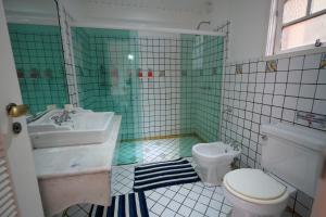 a green and white bathroom with a toilet and a sink at Casa da Ilha & SPA in Abraão