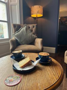 a table with two cups of coffee and a slice of cake at Colcombe Castle Hotel in Colyton +67 photos