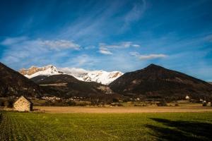 a mountain range with a green field and a house at Eden des Cimes, La Joue du Loup in La Joue du Loup