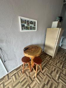 a wooden table with two stools and a refrigerator at Alecrim Cantinho na Canastra in São Roque de Minas