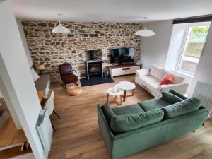 ein Wohnzimmer mit einer grünen Couch und einer Steinmauer in der Unterkunft Tata Jacqueline, grand gîte proche mer, Bretagne in Plouha