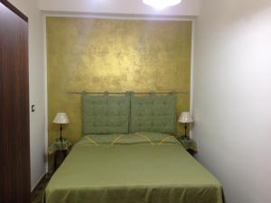 a bedroom with a green bed with two lamps at Casa Terme in Sciacca
