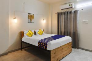 a bedroom with a bed with yellow and blue pillows at SPOT ON Hotel Blue Moon in Nagpur