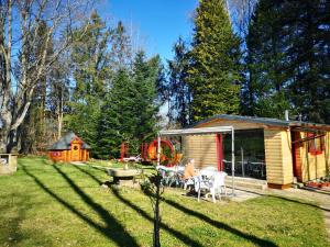 a woman sitting in a yard next to a cabin at Chalet aux 3 Ours , Kota-Grill, sauna in Le Val-dʼAjol