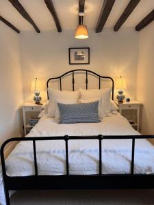 a bedroom with a bed with white pillows and two lamps at Pear Tree Cottage in the Cotswolds in Mickleton