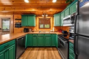 a kitchen with green cabinets and a black refrigerator at Smoky Haven Retreat By Beyond Expectations in Pigeon Forge